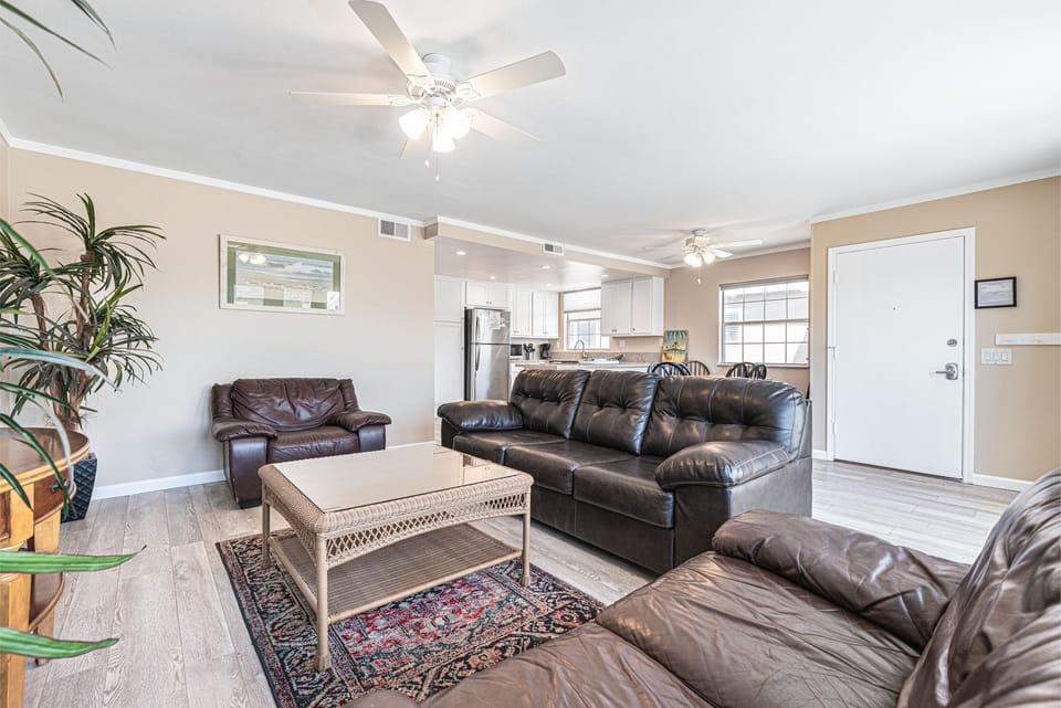 Vantage point from this upper unit's front French doors toward kitchen, living room and dining area. Ceiling fans and wood laminate flooring throughout main living areas.
                