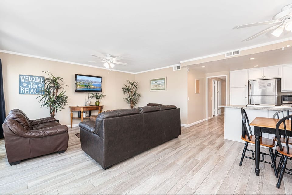 Vantage point from this upper unit's front French doors toward kitchen, living room and dining area. Ceiling fans and wood laminate flooring throughout main living areas.
                