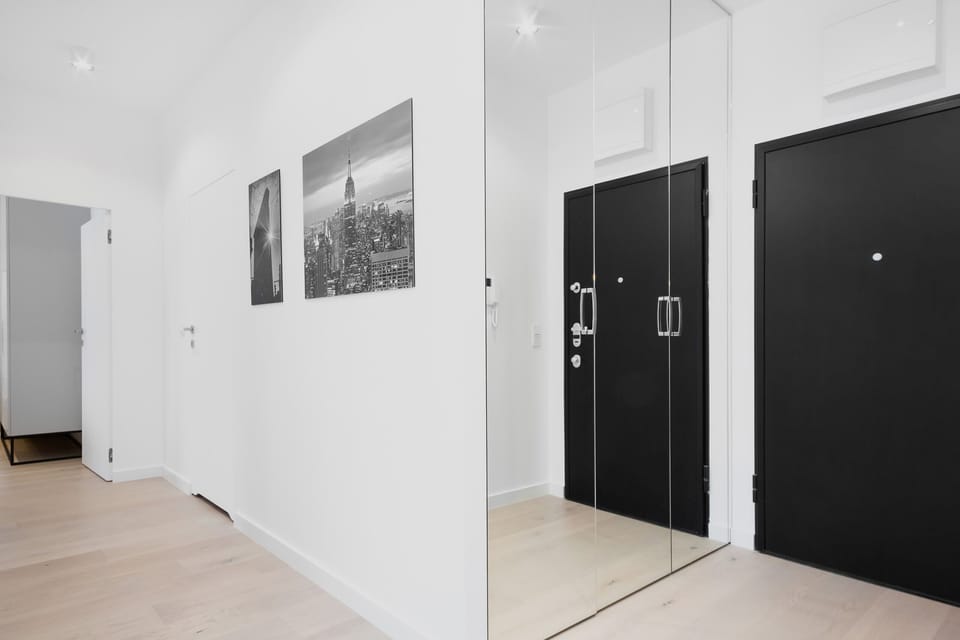 Hallway with white walls and a spacious wardrobe by the front door. The wardrobe doors are mirrors. 