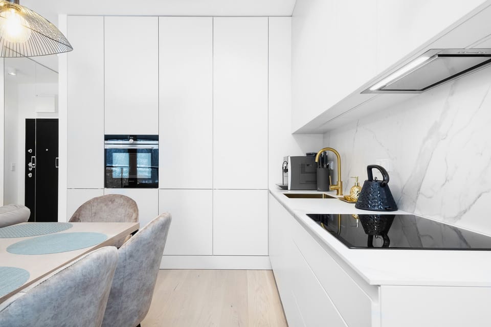 Kitchenette with white cabinets and quality appliances. The decor harmoniously harmonises with the rest of the room. 