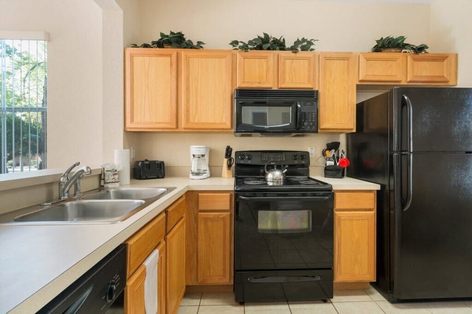 Fully equipped kitchen with wooden cabinets and black appliances.