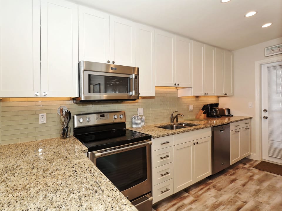 Modern, renovated, fully equipped kitchen with granite counters, glass tile backs splash...