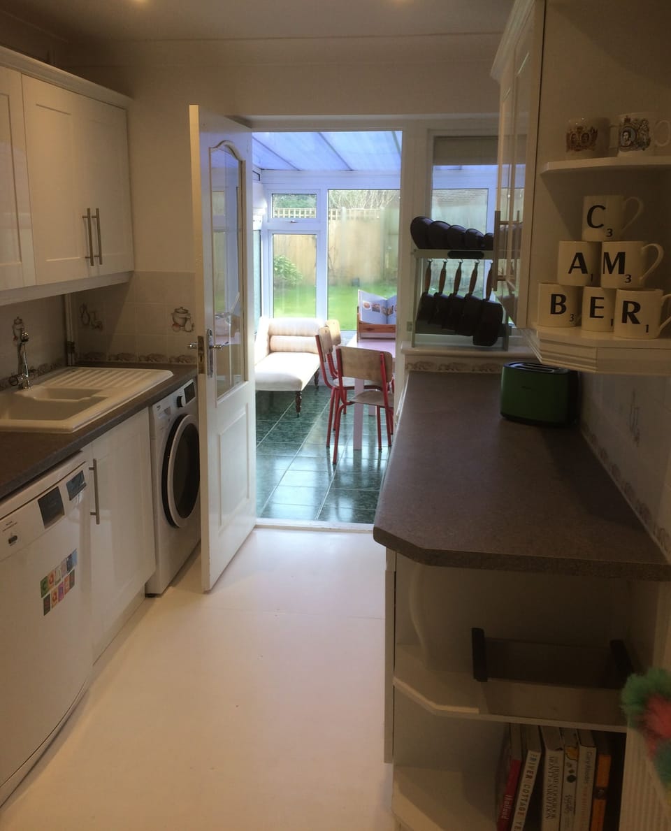Our galley kitchen leads out into the conservatory with our pink dining table