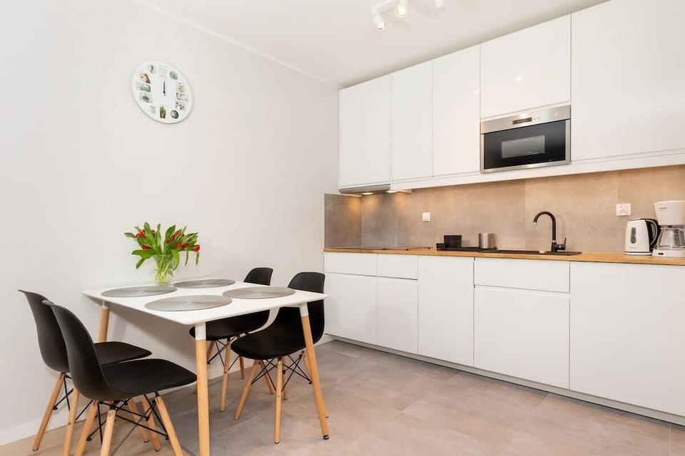 A compact dining area with a modern table and chairs, positioned near a large window. The decor is minimalist, with a focus on functionality and style.