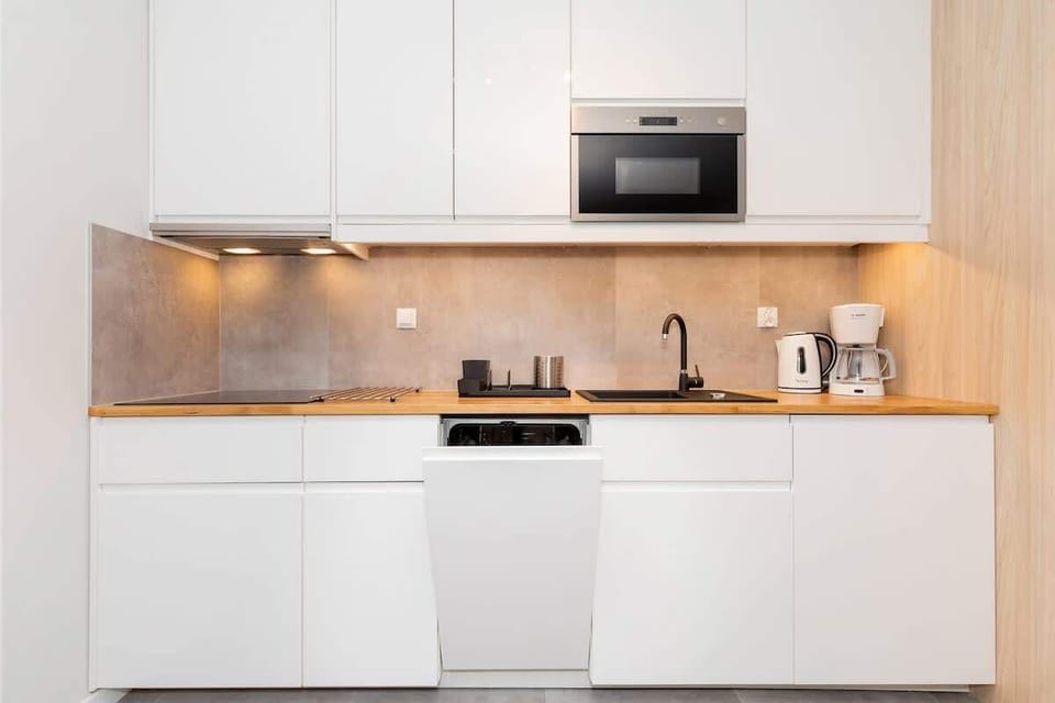 A sleek, white kitchen with modern appliances and plenty of countertop space, designed for efficiency and convenience.