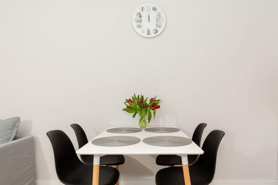 A compact dining area with a modern table and chairs, positioned near a large window. The decor is minimalist, with a focus on functionality and style.