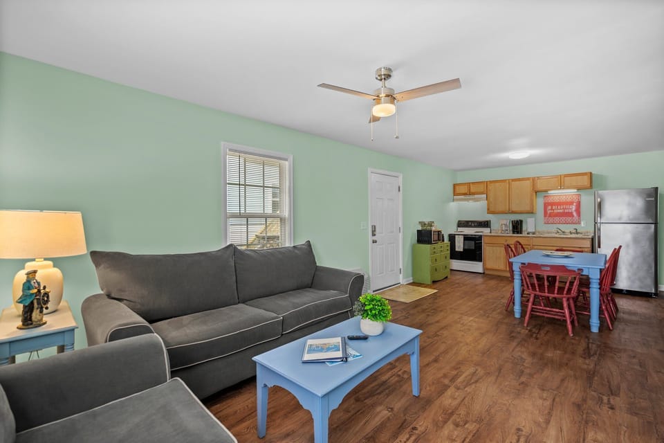 Unwind in your open-concept living space with comfortable gray seating, soothing mint walls, and a full kitchen ready for your culinary adventures.