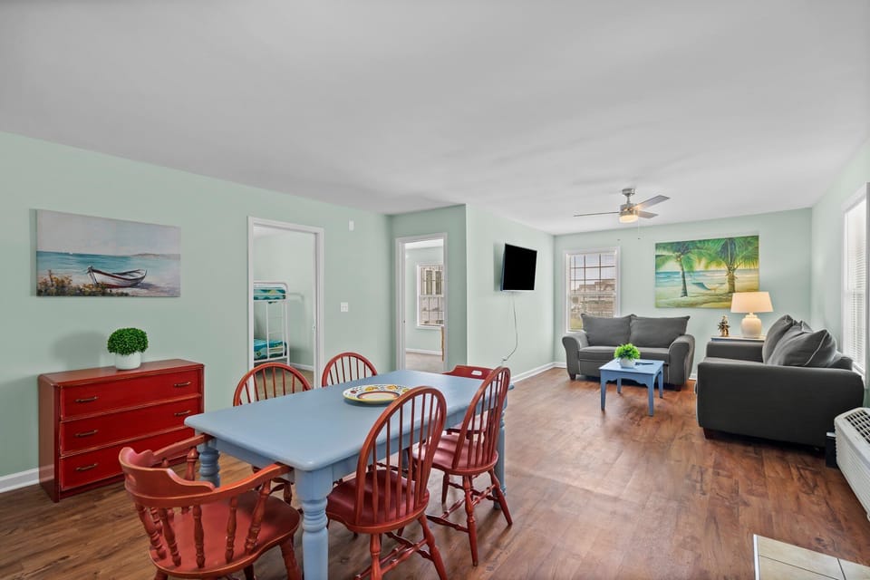 Relax in your bright, coastal-themed living space where soothing mint walls and tropical artwork create a serene beach house atmosphere.