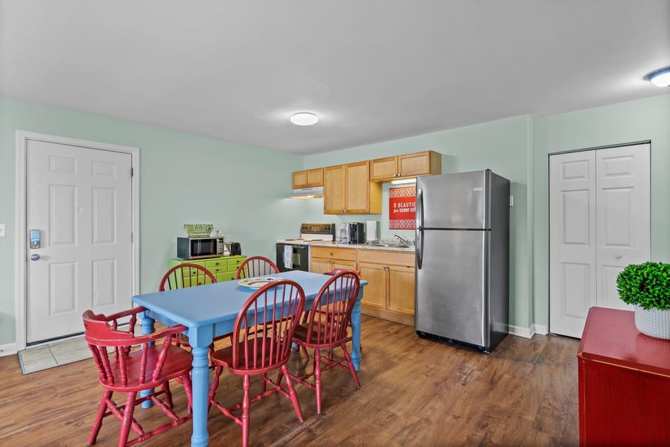 Your cheerful kitchen and dining space features colorful red chairs around a blue table, perfect for family meals and morning coffee.