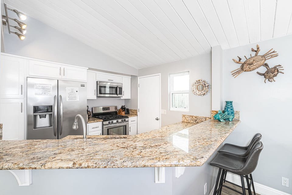 Kitchen includes bar seating, large and small appliances, dishes, utensils, cookware, and bakeware.
                