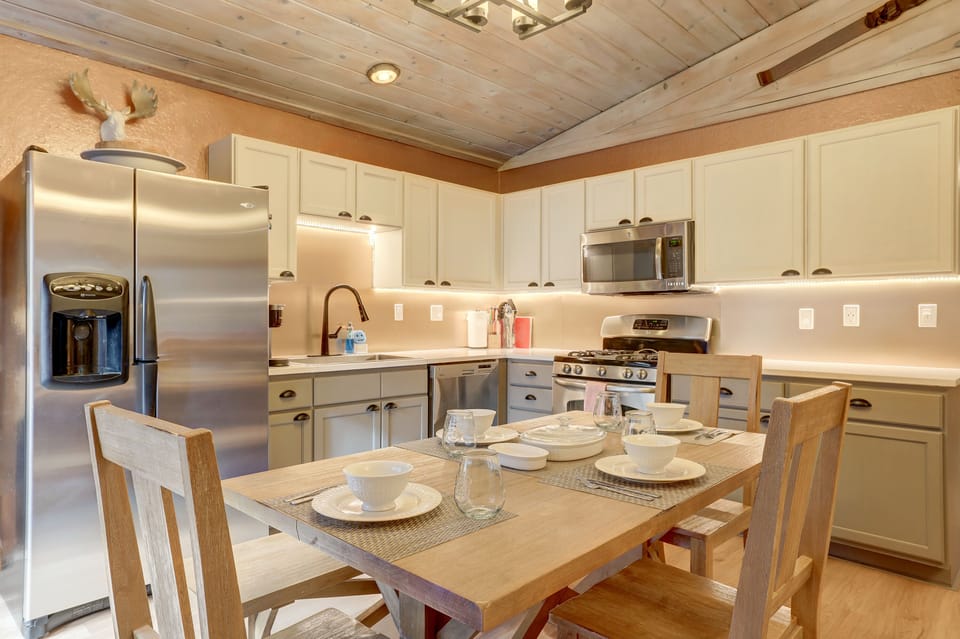 Open kitchen with and a dining table with chairs, a bench and place settings
