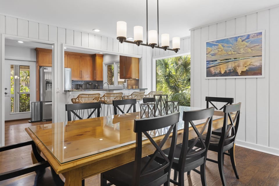 Dining room with table that seats 8 leading to kitchen with 4 barstools