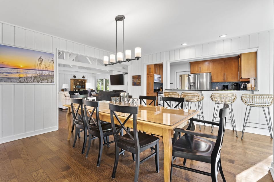 Dining room with table that seats 8 leading to kitchen with 4 barstools