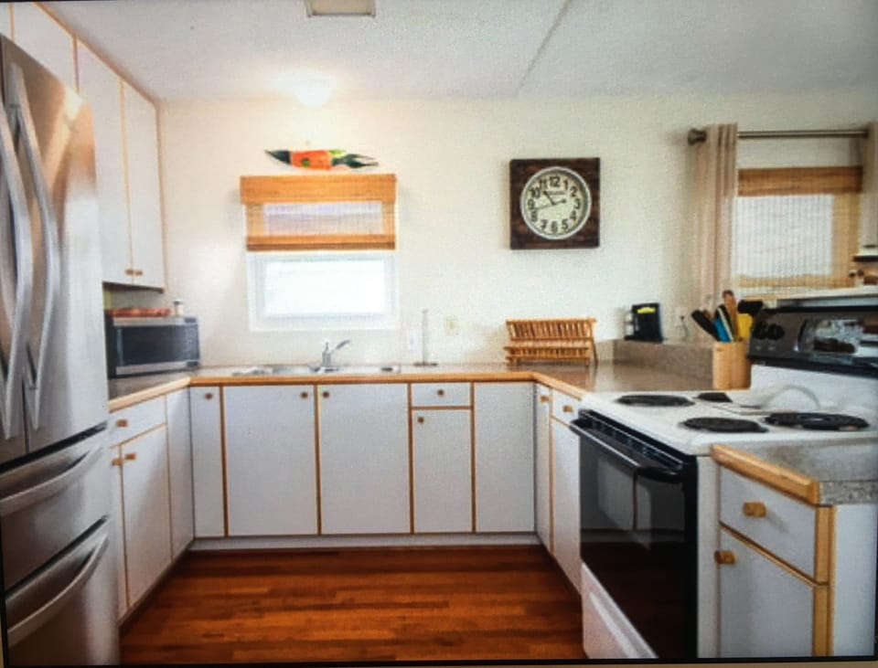 Open kitchen with lots of sunlight. Plenty of dishes, glasses and cookware.