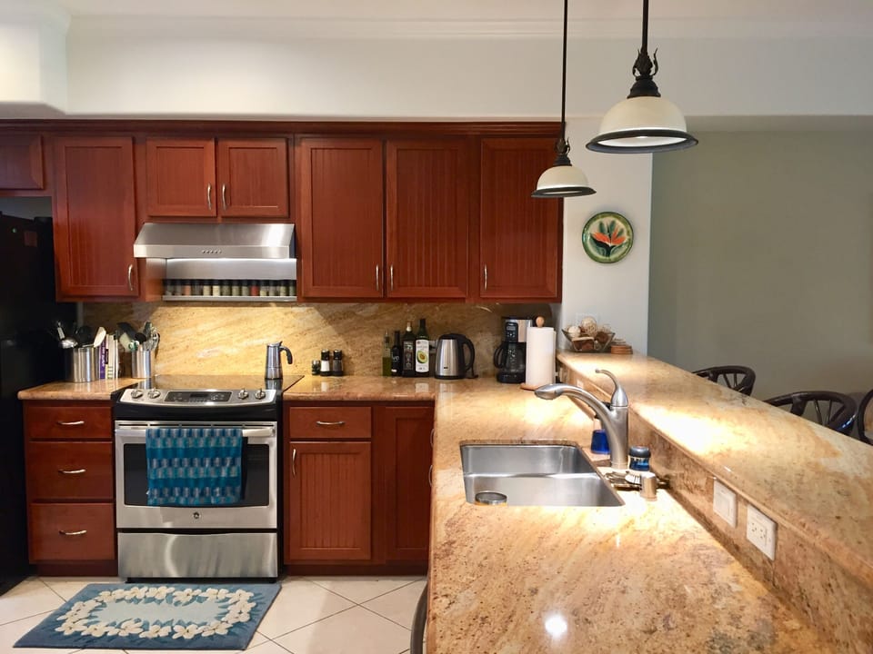 One part of the kitchen.  3 swivel barstools.  Tile floors, granite counters.