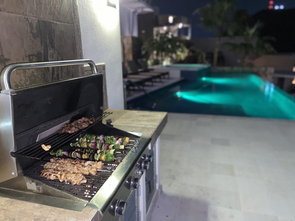 Nighttime view of the bbq, pool and jacuzzi in the background