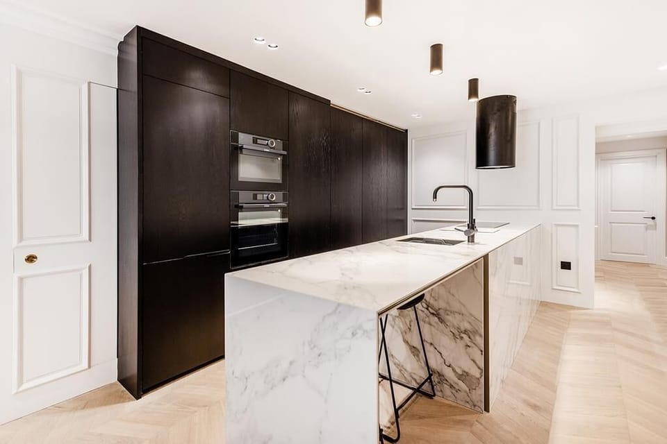 Designer kitchen with marble breakfast bar and integrated appliances. 