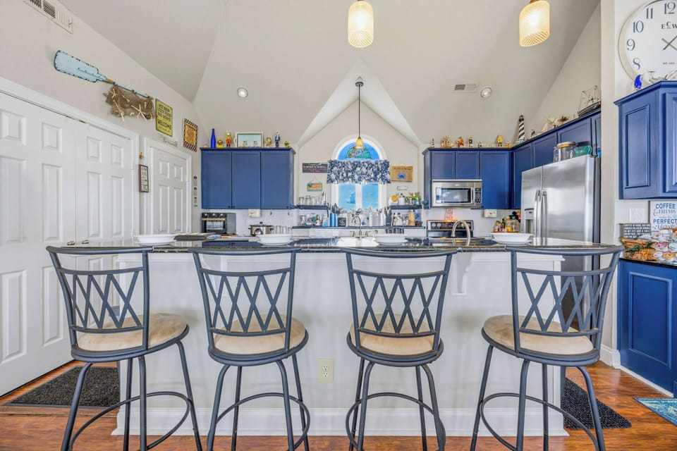 Gather around this spacious island for morning coffee or meal prep in your fully equipped kitchen. The bright blue cabinets and vaulted ceilings create a cheerful, open atmosphere perfect for making memories.