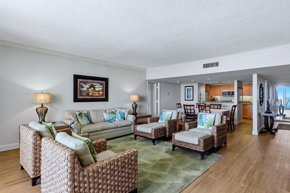 Unwind in your spacious tropical-inspired living room, where wicker chairs and palm-printed pillows create a resort atmosphere. The open layout connects seamlessly to your dining area and kitchen.