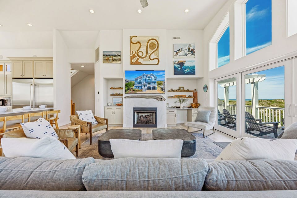 Sink into plush sofas by the fireplace and gaze out at stunning coastal views—this bright, open living space is your perfect spot to unwind after a day at the beach.