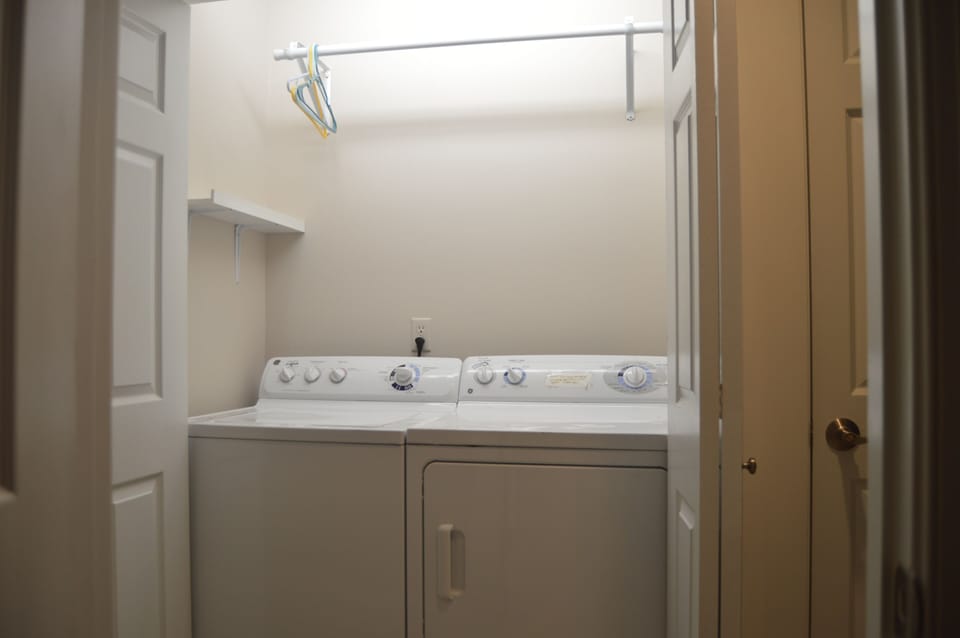 Bright laundry area with washer and dryer in upstairs hallway.