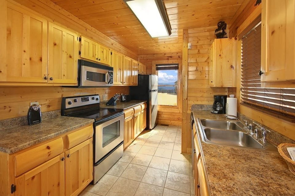 - Fully equipped kitchen with stainless steel appliances and cabin charm   - Wooden cabinetry and scenic window views create a cozy workspace   - Ideal for preparing hearty mountain meals with family and friends