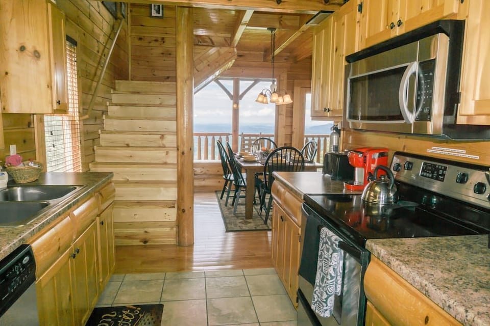 - Warm cabin kitchen opens to dining area with stunning mountain backdrop   - Modern appliances blend with rustic wooden interiors   - Cook and dine surrounded by natural light and Smoky Mountain beauty
