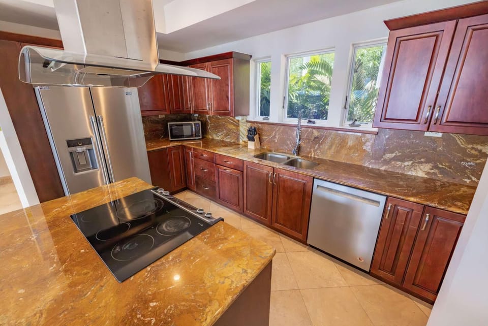 Kitchen features polished brown granite countertops, cherry wood cabinets, stainless steel appliances, and three windows with garden views.