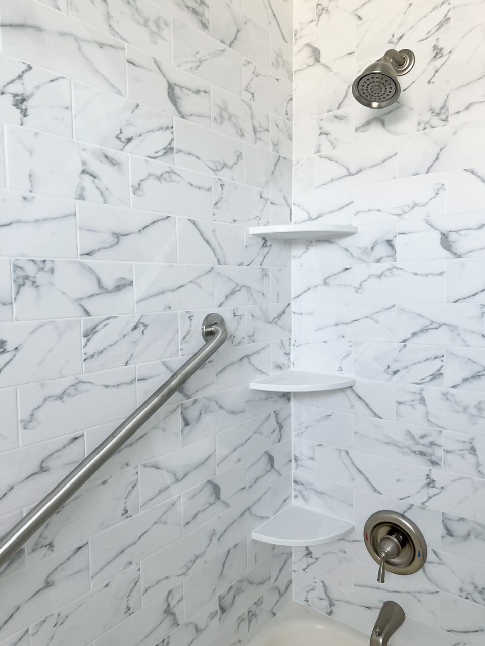 Tub/shower with grab bars and plenty of shelves.