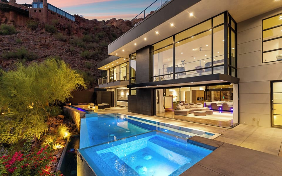 Sleek estate w/ infinity pool, spa & glowing interiors against Camelback views.