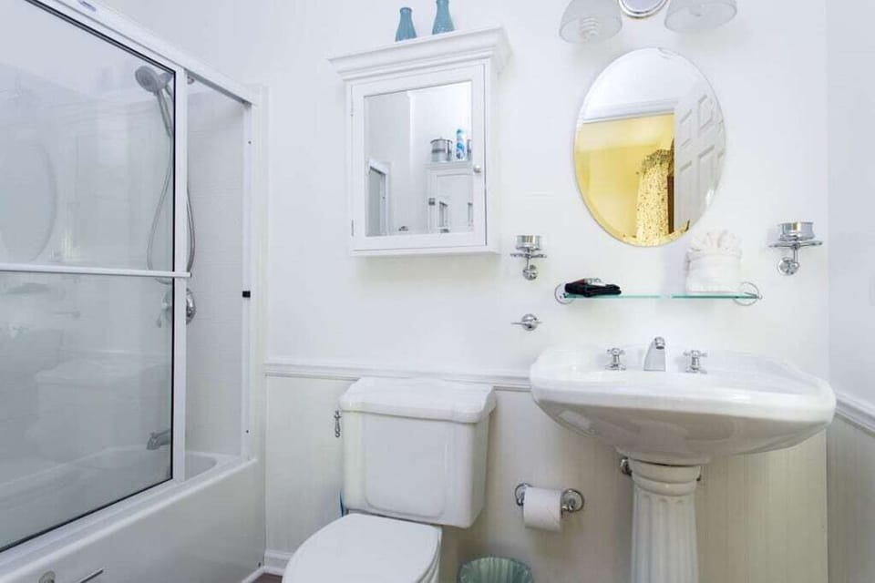 The full bath has a pedestal sink, tub/shower combo with sliding doors, and lovely Colonial-style chrome hardware.