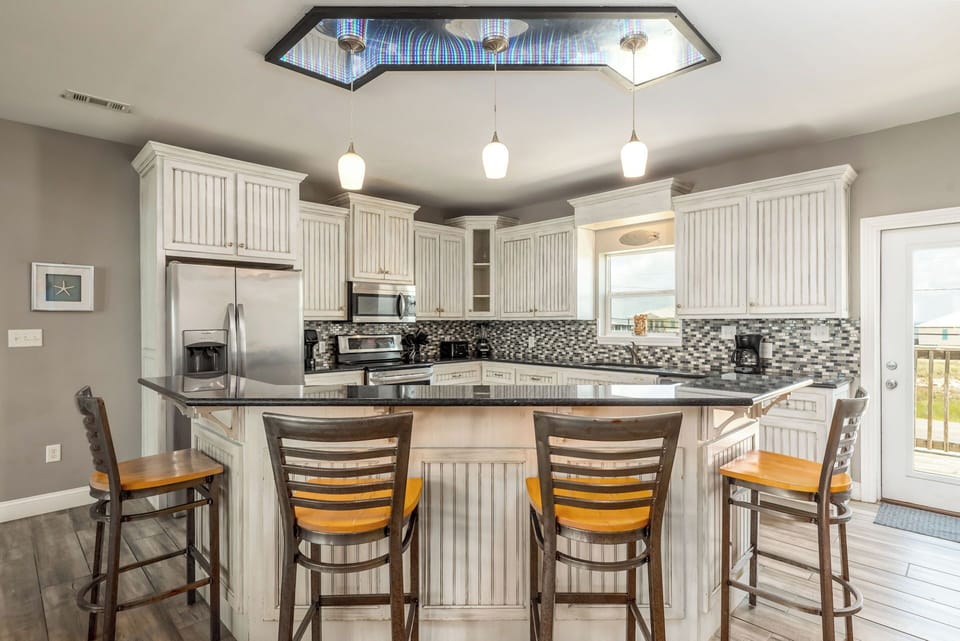 Your fully equipped kitchen features granite countertops, stainless appliances, and spacious breakfast bar seating for family meals and morning coffee.