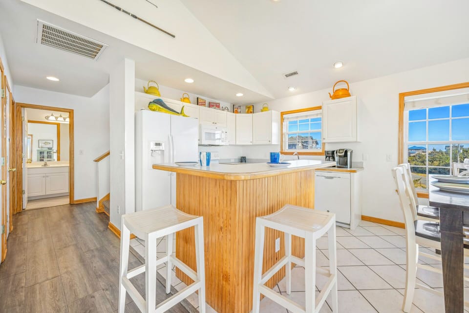 Prepare meals in your bright, coastal-inspired kitchen with bamboo island seating and ocean views through large windows.