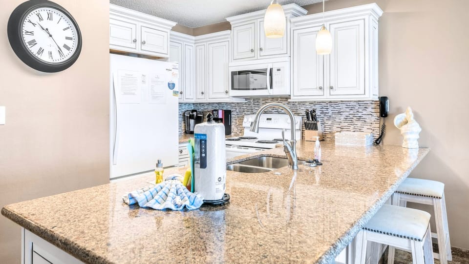 A crisp kitchen with granite counters and full appliances.