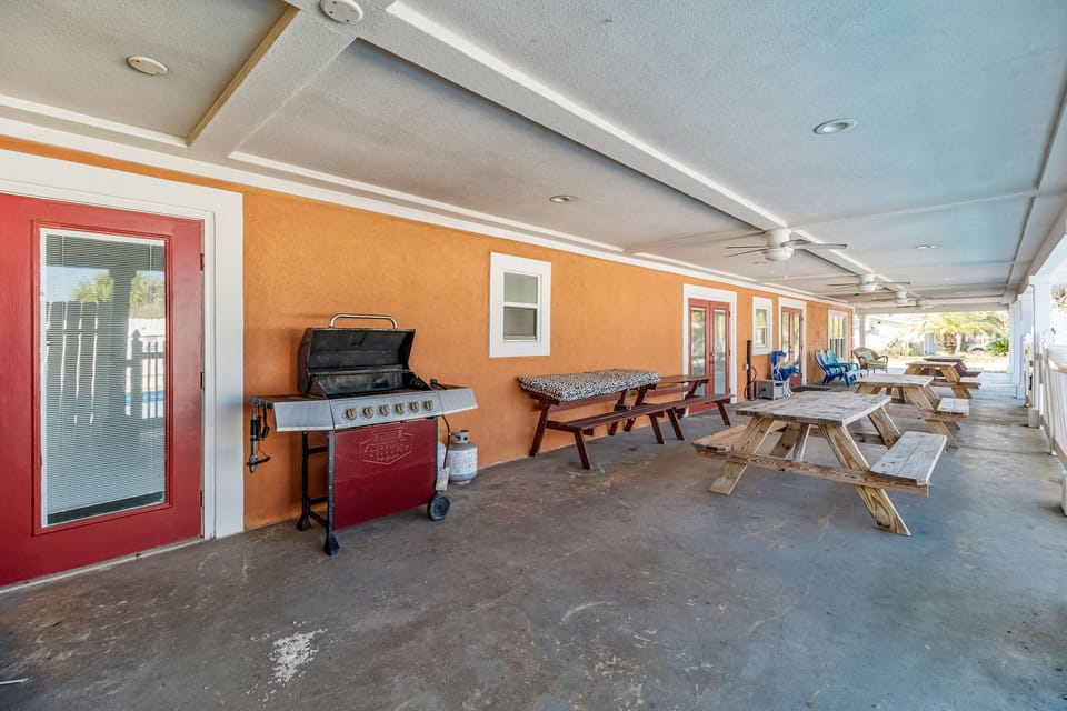 Dining porch by saltwater pool with tables and large gas grill.