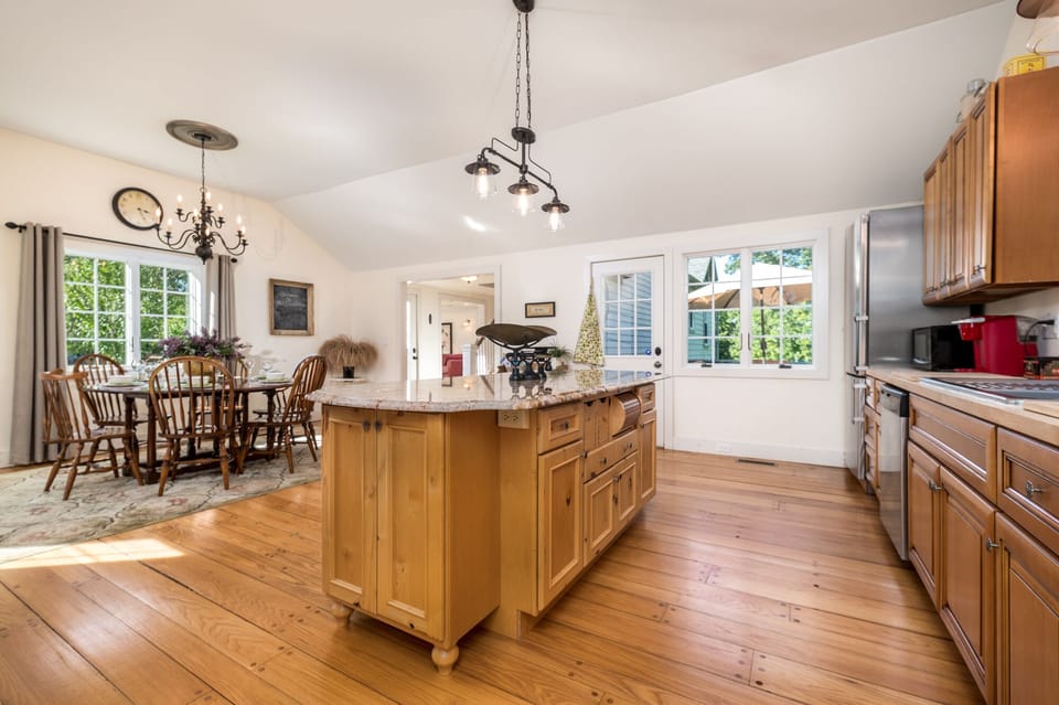 Granite kitchen island and original wood floor, with view of back deck