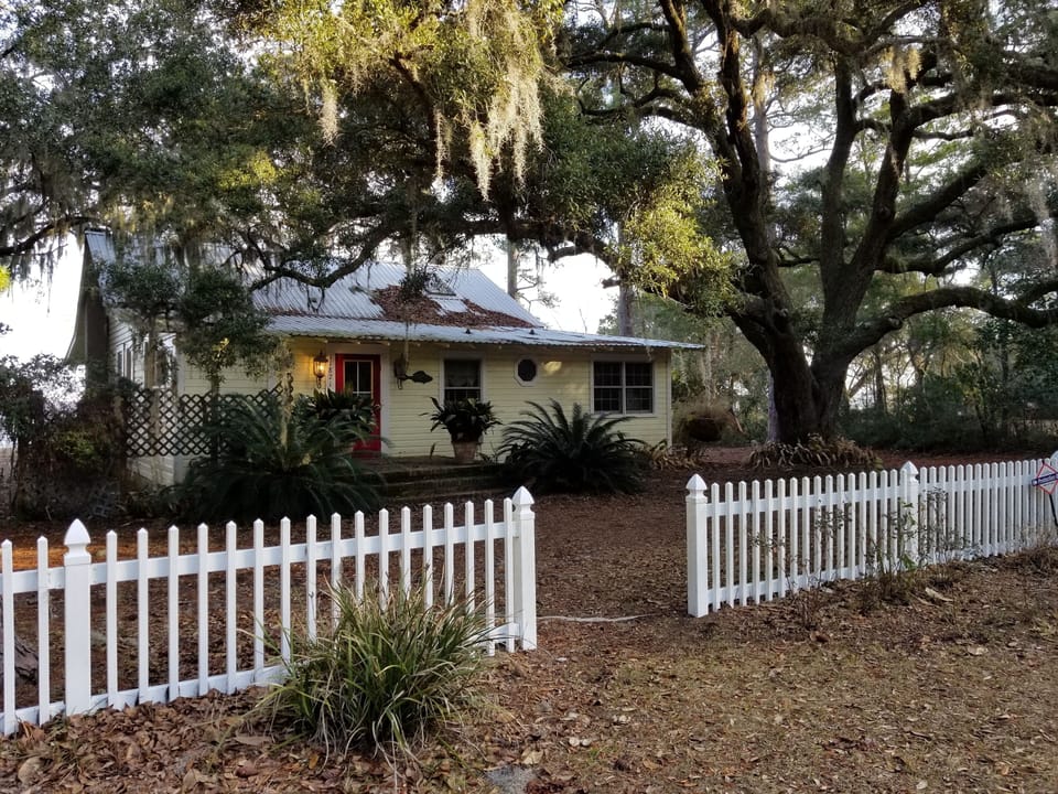 Front of cottage surrounded by live oaks, a picket fence and a 4 acre lot!