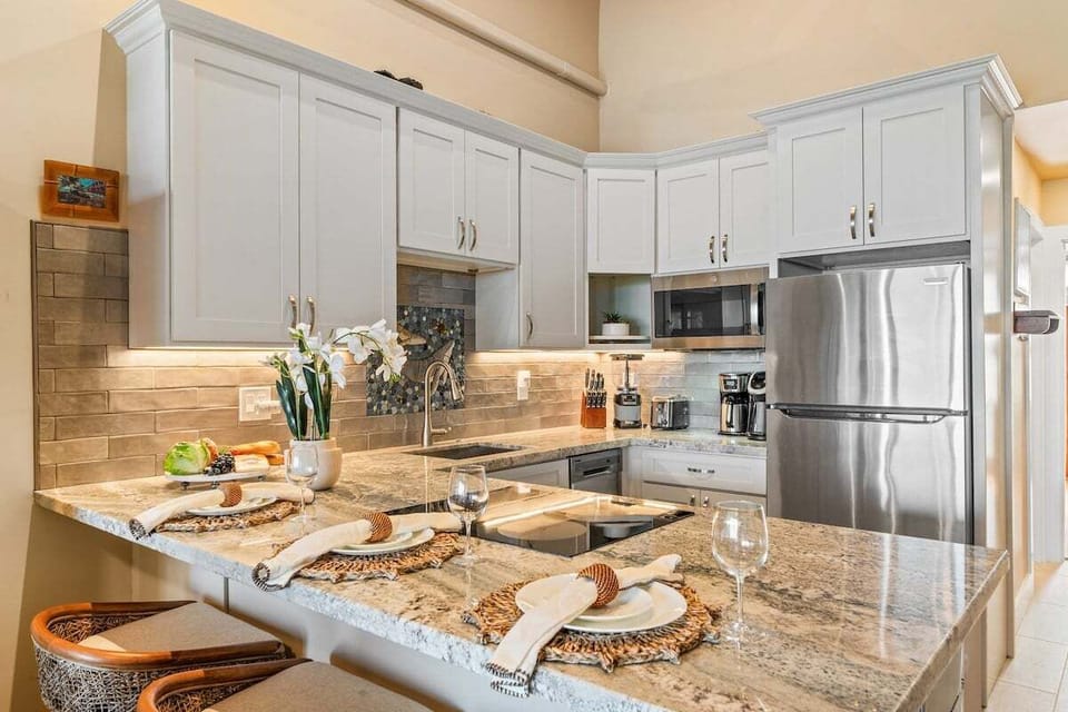 Fully equipped kitchen with granite counters, induction cooktop, and bar seating.