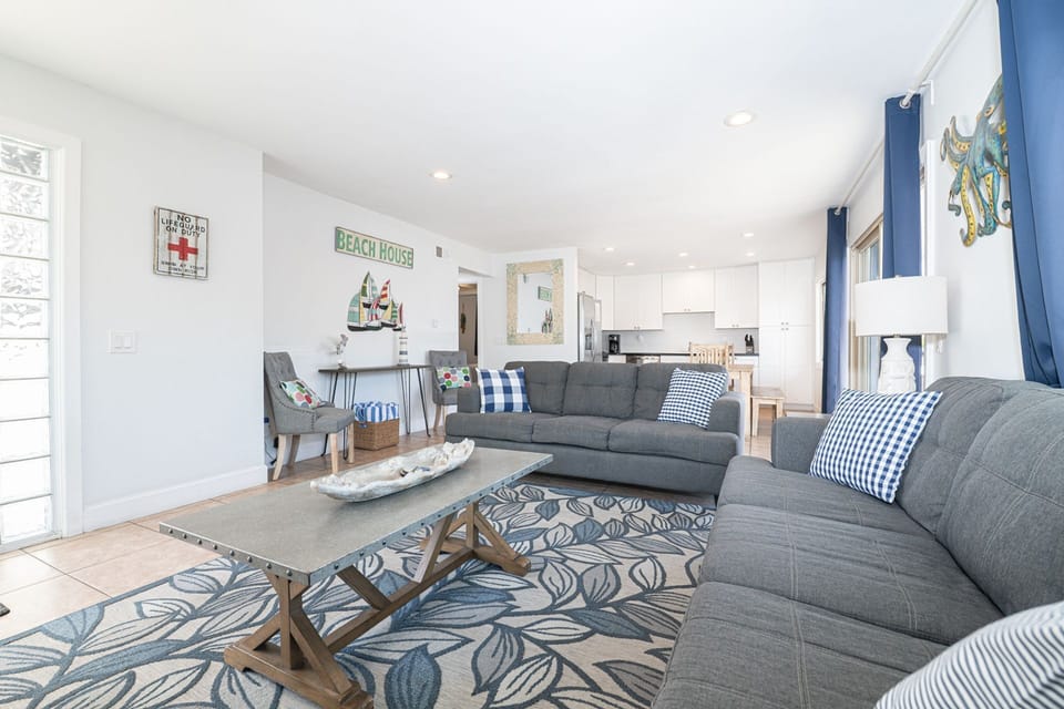 The living room invites easy conversation, afternoon lounging, and cozy evenings with the ocean only steps away
                