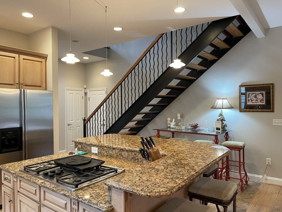 Large 2-tier island with 6 bar stools. Dacor gas stove in center & subzero wine