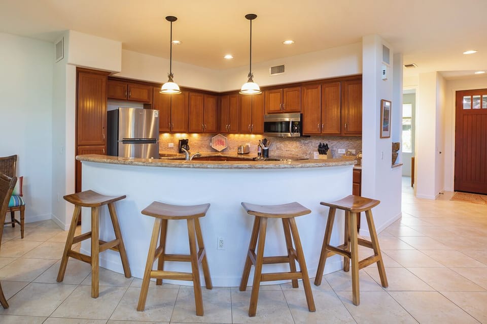 Spacious kitchen with bar seating and modern appliances, ideal for preparing meals or gathering with friends.