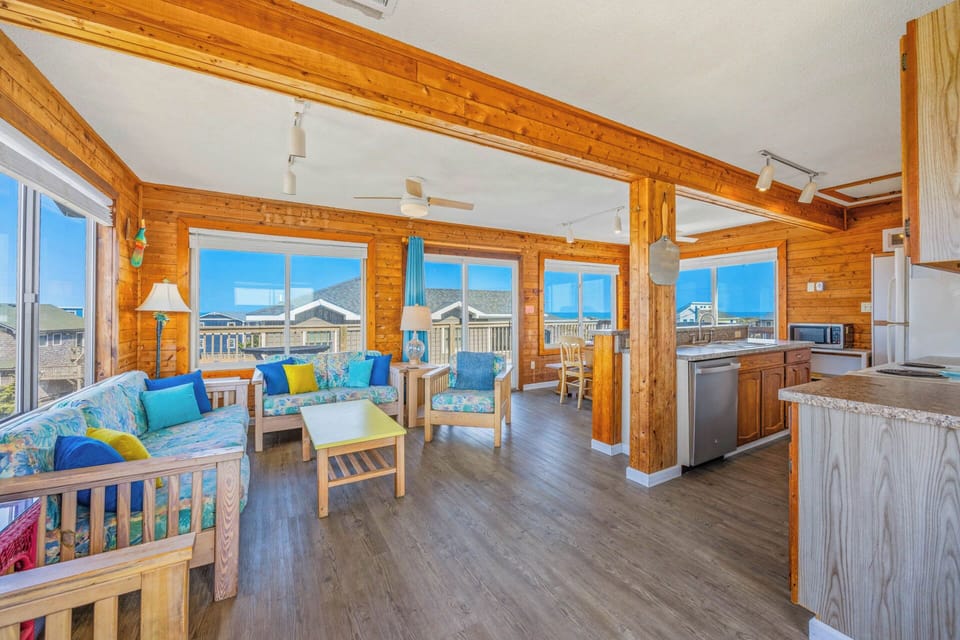 Bright, vaulted ceilings and warm wood beams frame your open-concept living space, where coastal blues invite you to unwind while ocean views peek through every window.