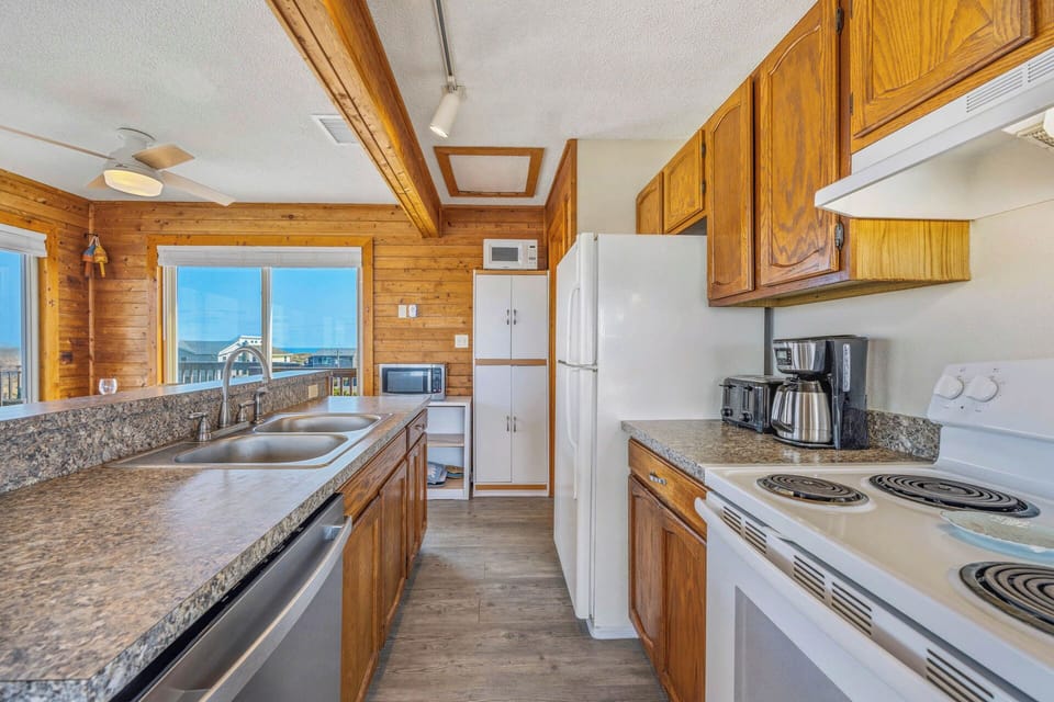 Picture yourself cooking in this fully equipped kitchen with warm wood cabinetry, granite countertops, and stunning lake views streaming through the windows—your perfect mountain retreat awaits.