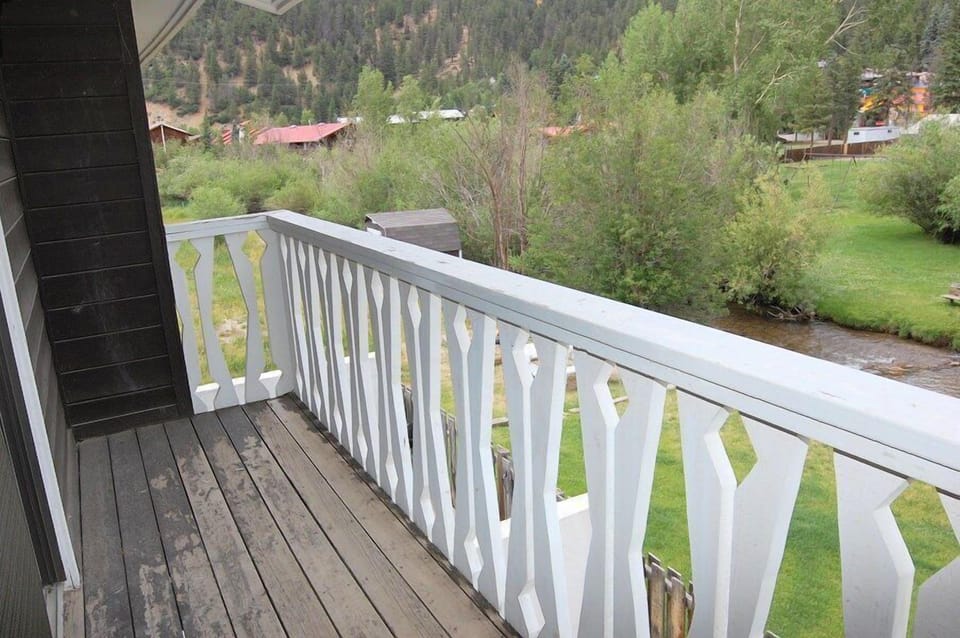 A secluded mountain valley retreat set beside a peaceful stream and dense forest. This location offers a quiet, natural escape surrounded by wooded hillsides and scattered neighboring properties.