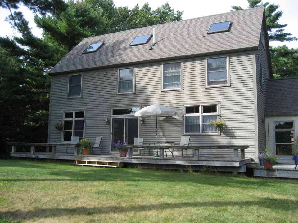Back of the home with large backyard and swingset 