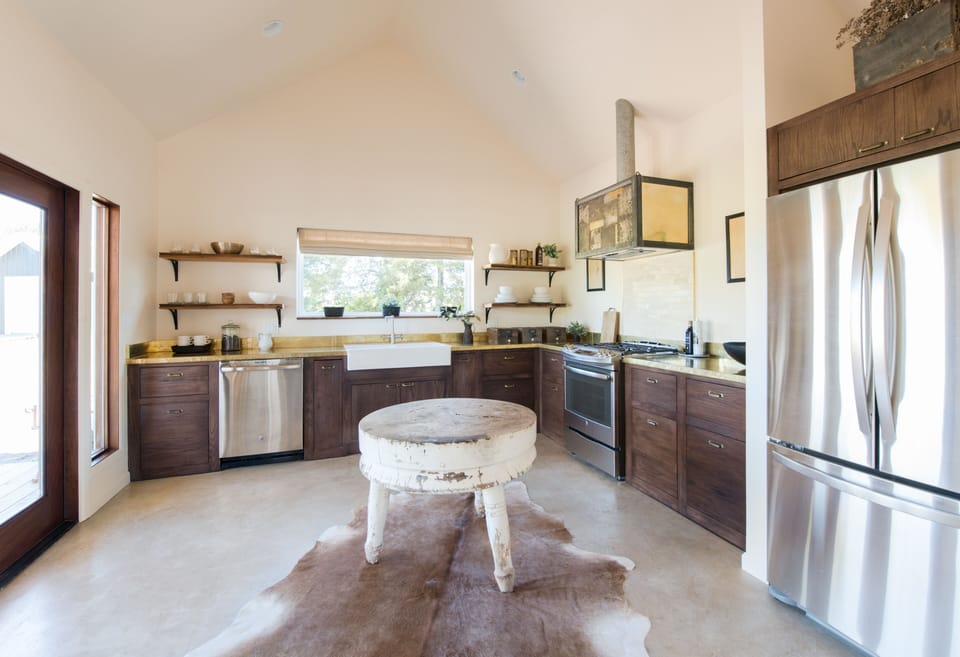 Full kitchen with gas stove, large fridge, brass countertops and custom hood