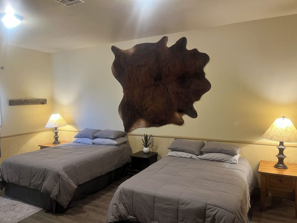 Spacious bedroom with two queen beds and a desk.