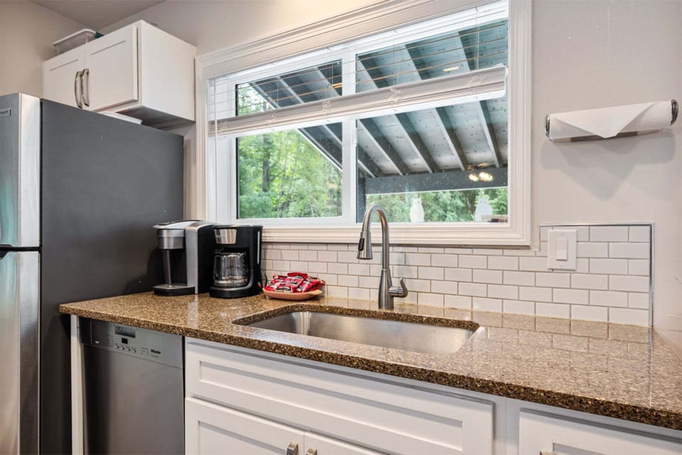 Morning coffee starts beside the sink, with a leafy view over the covered deck.