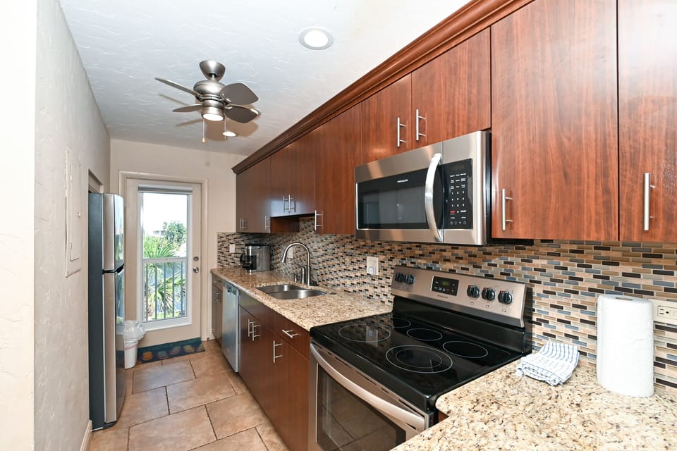 Modern, renovated, fully equipped kitchen with granite counters, glass tile backs splash...