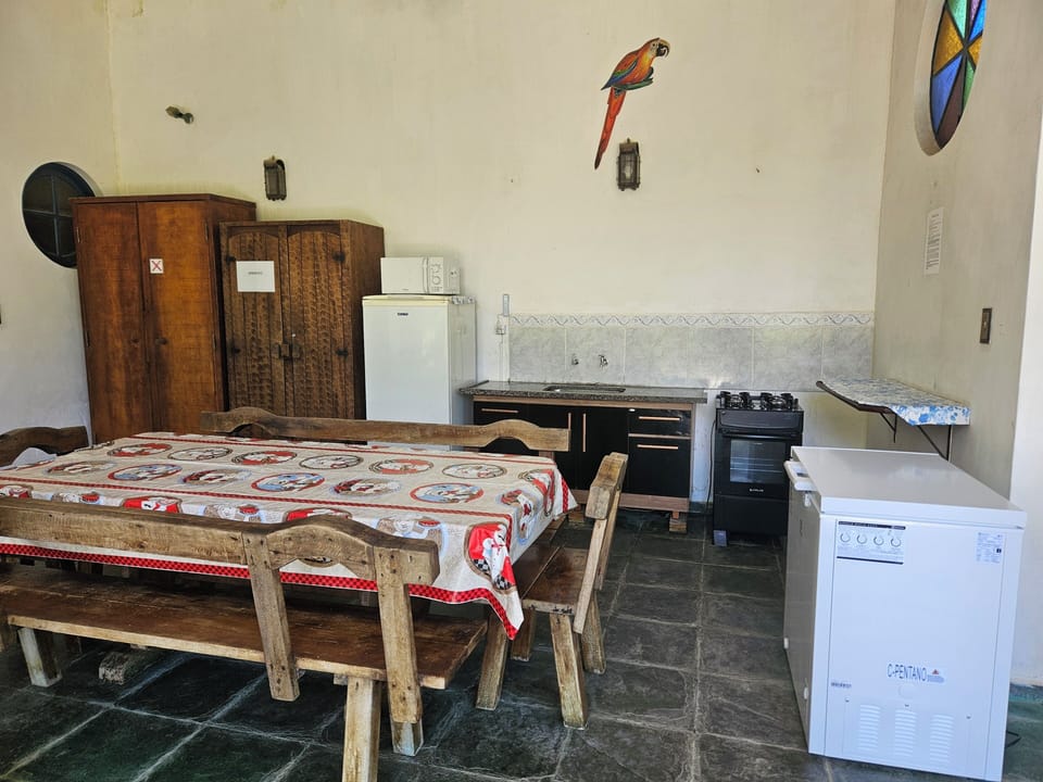 Cozinha com geladeira, micro-ondas, gabinete e pia, armário com utensílios.